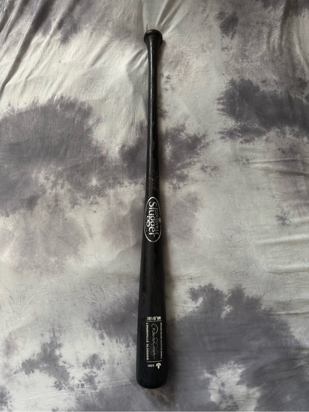 This is a black Louisville Slugger bat, model etched autographed